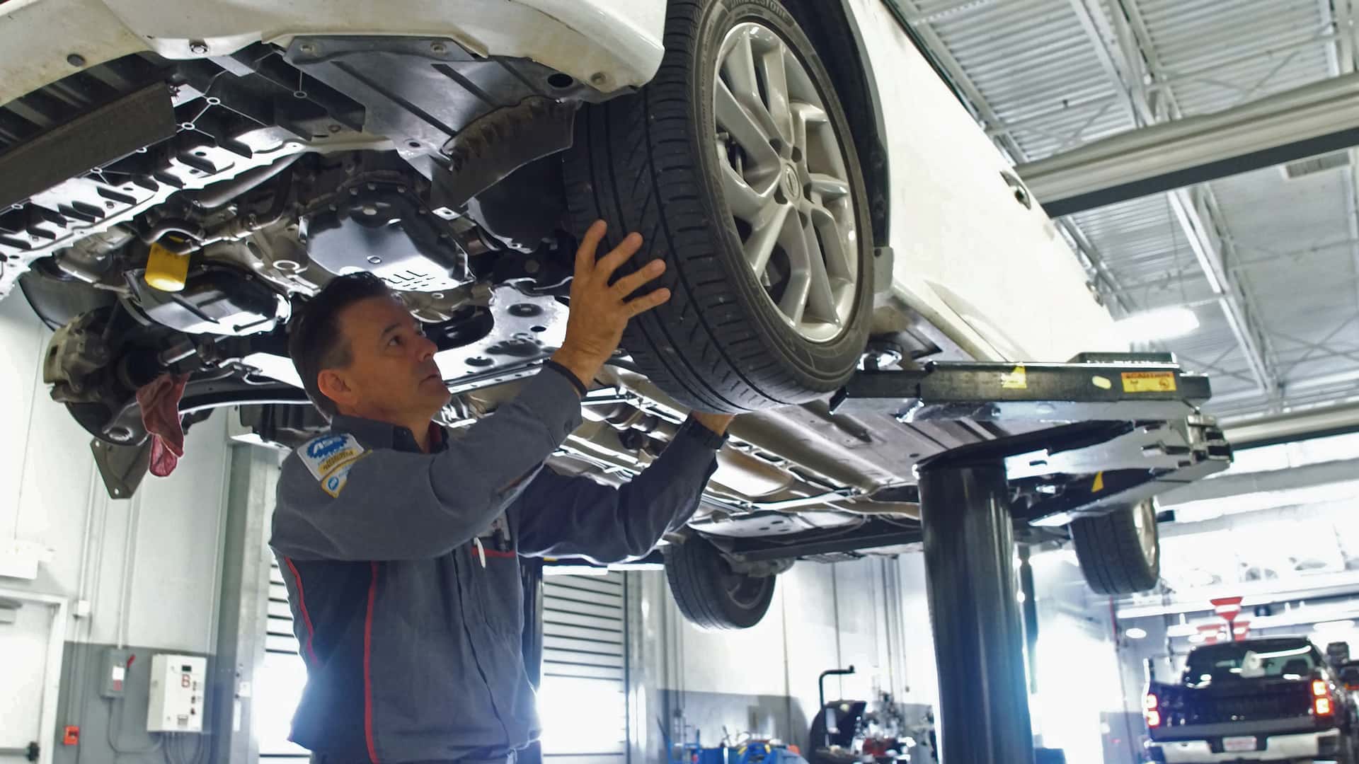 Mechanic standing by silver Nissan SUV