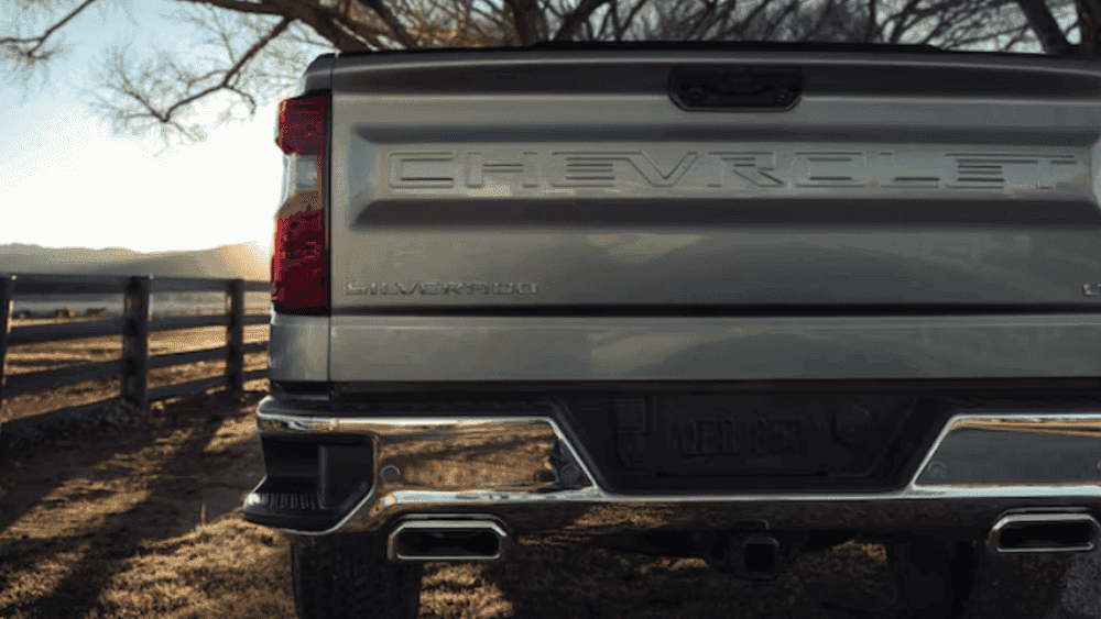 Rear view of a 2026 Chevrolet Silverado showing the tailgate design and dual exhaust parked on a rural property near Spindale, NC