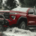 2026 GMC Canyon driving through rocky terrain and water, demonstrating towing strength and cold-weather durability contractors rely on in Spindale, NC