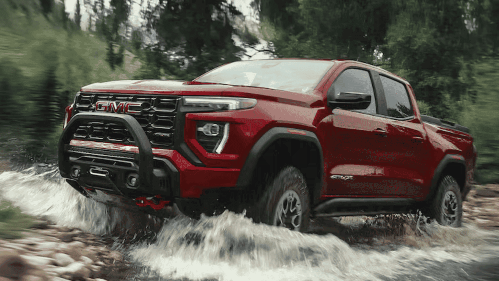 2026 GMC Canyon driving through rocky terrain and water, demonstrating towing strength and cold-weather durability contractors rely on in Spindale, NC