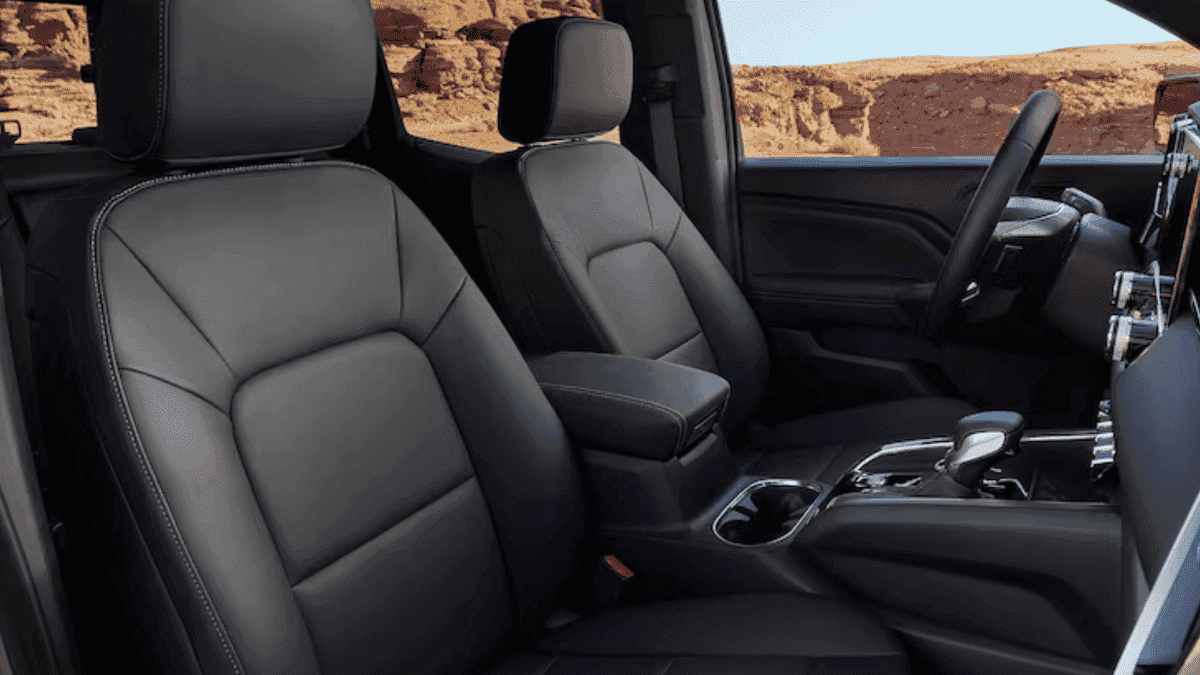 Front interior view of a 2026 GMC Canyon displaying a rugged dashboard design, touchscreen infotainment, and driver-focused layout