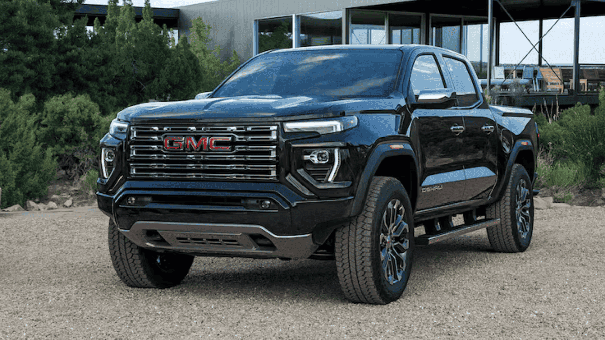 Exterior front view of a black 2026 GMC Canyon parked outdoors, showcasing its bold grille, elevated stance, and off-road styling
