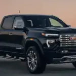 Front three-quarter view of a 2026 GMC Canyon Denali on a roadway at dusk, emphasizing turbo power and job-site reliability trusted by Ruth, NC tradespeople