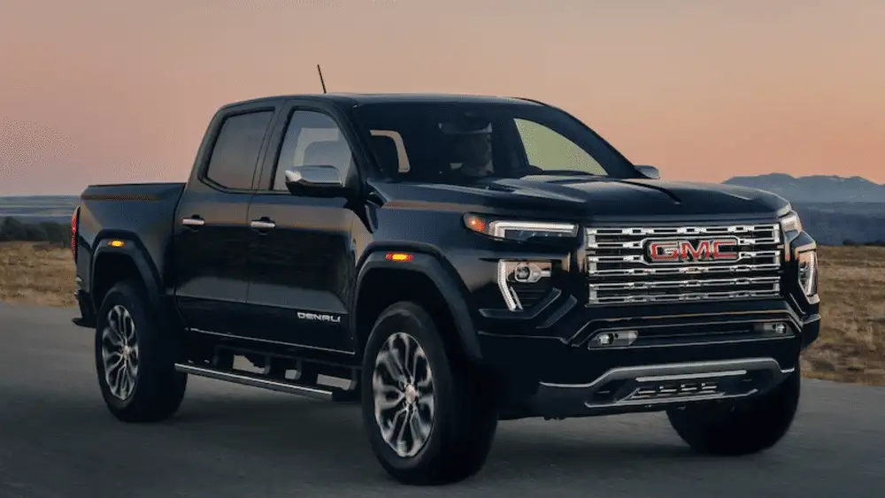 Front three-quarter view of a 2026 GMC Canyon Denali on a roadway at dusk, emphasizing turbo power and job-site reliability trusted by Ruth, NC tradespeople
