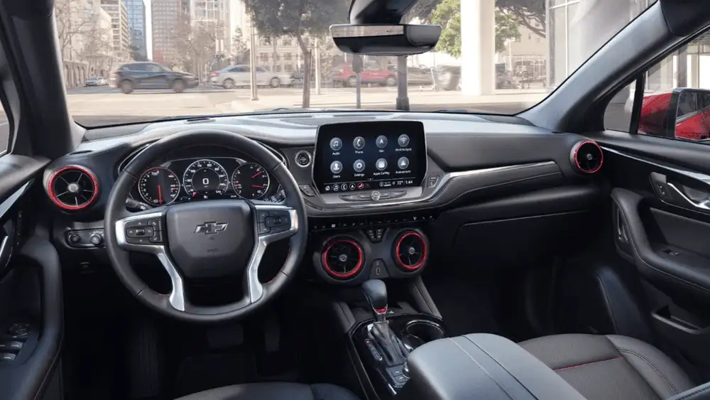 Interior dashboard of a 2026 Chevrolet Blazer with sporty steering wheel, touchscreen infotainment, and red accent vents near Ruth, NC