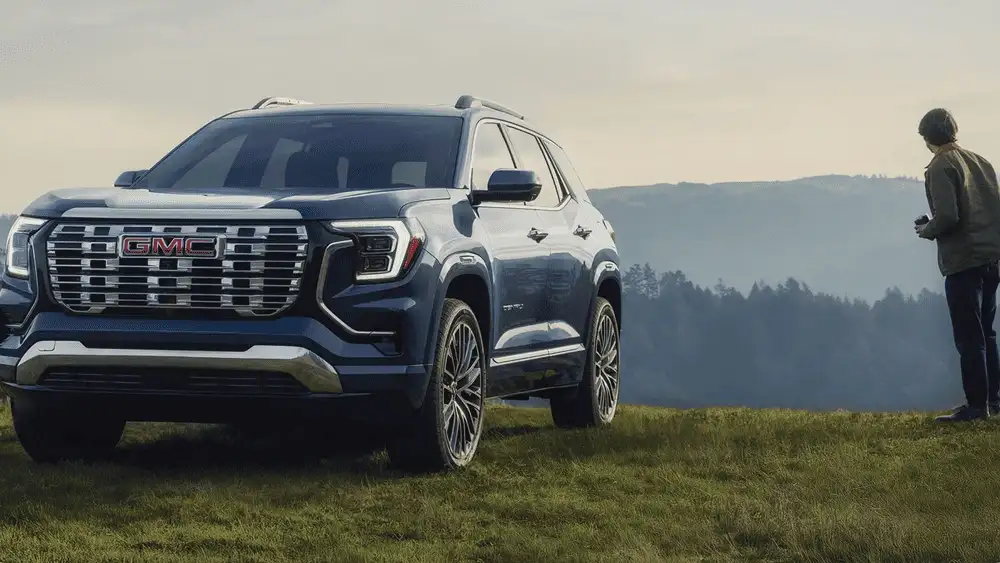 Exterior front three-quarter view of a 2026 GMC Terrain parked on open terrain, highlighting bold grille styling and SUV capability near Ruth, NC