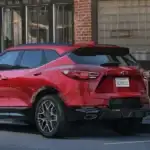 Red 2026 Chevrolet Blazer parked curbside outside a storefront, highlighting stylish SUV design for first-time buyers near Ruth, NC