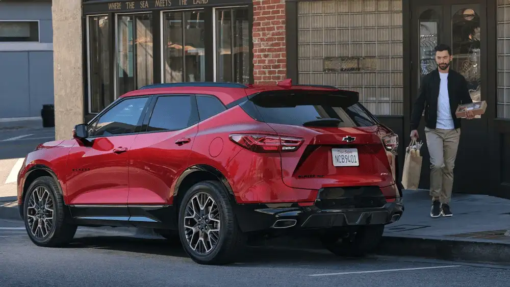 Red 2026 Chevrolet Blazer parked curbside outside a storefront, highlighting stylish SUV design for first-time buyers near Ruth, NC