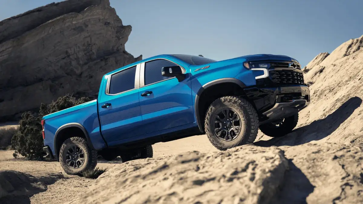 Blue 2026 Chevrolet Silverado near Ruth, NC climbing rocky terrain, showcasing off-road capability and lifted truck performance