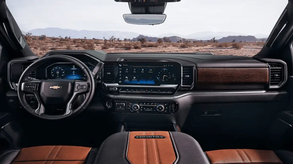 2026 Chevrolet Silverado HD interior dashboard near Ruth NC featuring dual digital displays, Bowtie steering wheel, and two-tone Carhartt Country leather seats with desert landscape visible through windshield