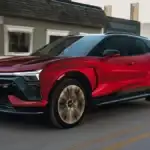 Plug in and head out with the 2026 Chevrolet Blazer EV around Ruth NC in red and black two-tone SS trim driving through a small town street with illuminated Bowtie grille and turbine-style alloy wheels