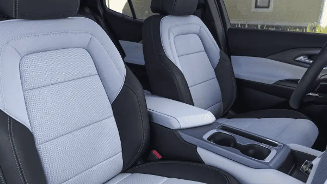 2026 Chevrolet Equinox EV front seat interior near Ruth NC featuring two-tone gray and black leather bucket seats with center armrest and cup holders