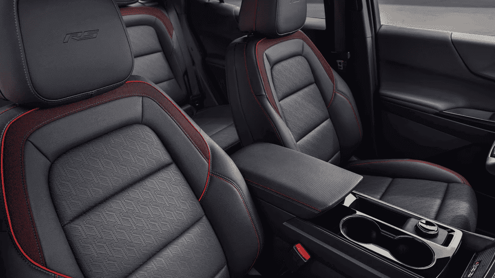 2026 Chevrolet Equinox RS near Ruth NC in red and black two-tone finish with Bowtie grille, RS badging, black roof, and dark alloy wheels driving through an urban street