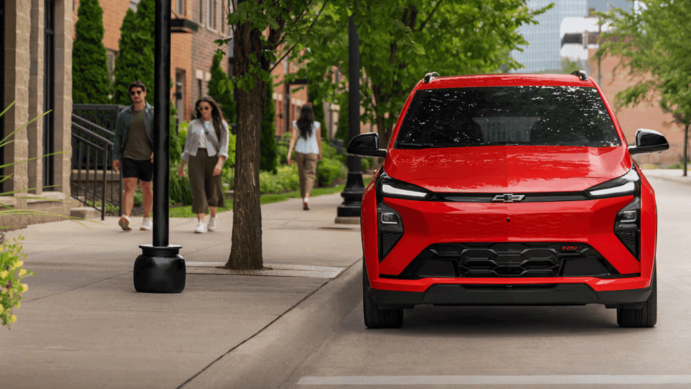 2027 Chevrolet Bolt RS near Ruth NC in red with Bowtie grille and LED headlights parked on a tree-lined urban street