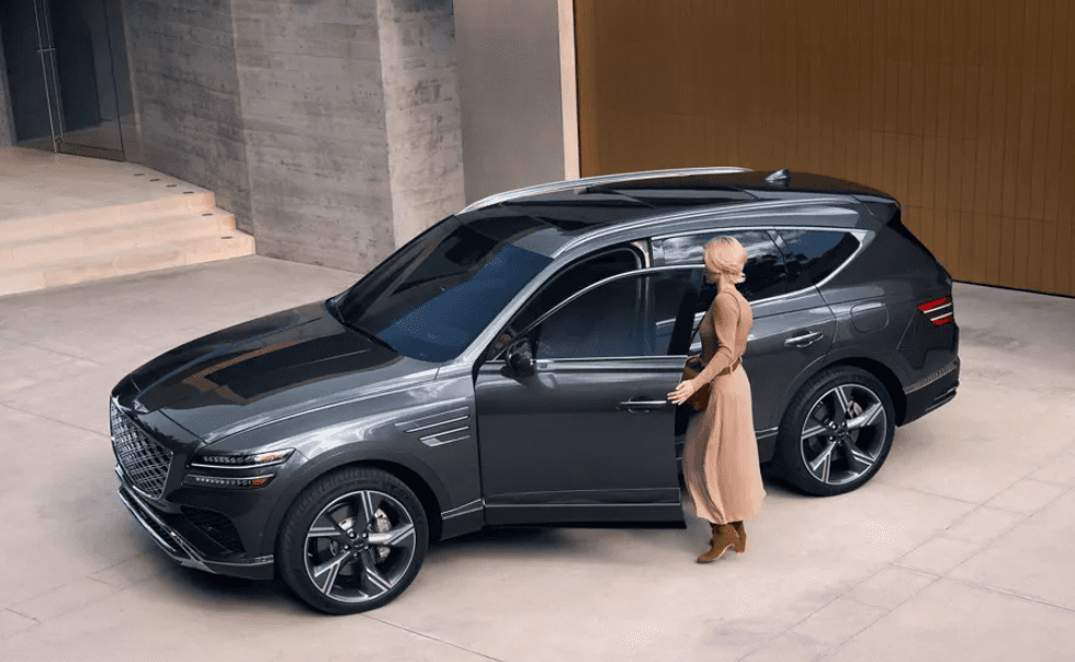 Green 2027 Genesis GV80 with women entering driver seat