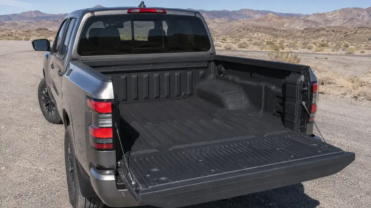 Nissan Frontier bed with the tailgate lowered, showing the spray-in bedliner and the wheel well housings