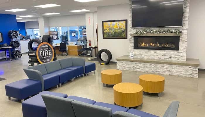 Customer lounge with a fireplace, seating and a TV at Goode Motor