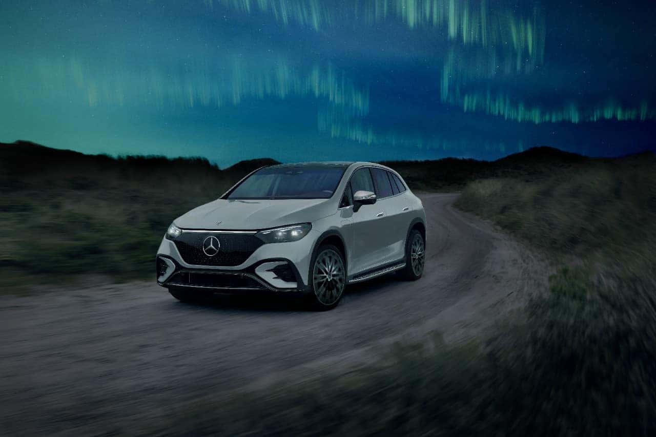 "Mercedes-Benz EQ driving on a scenic road with mountains in the background