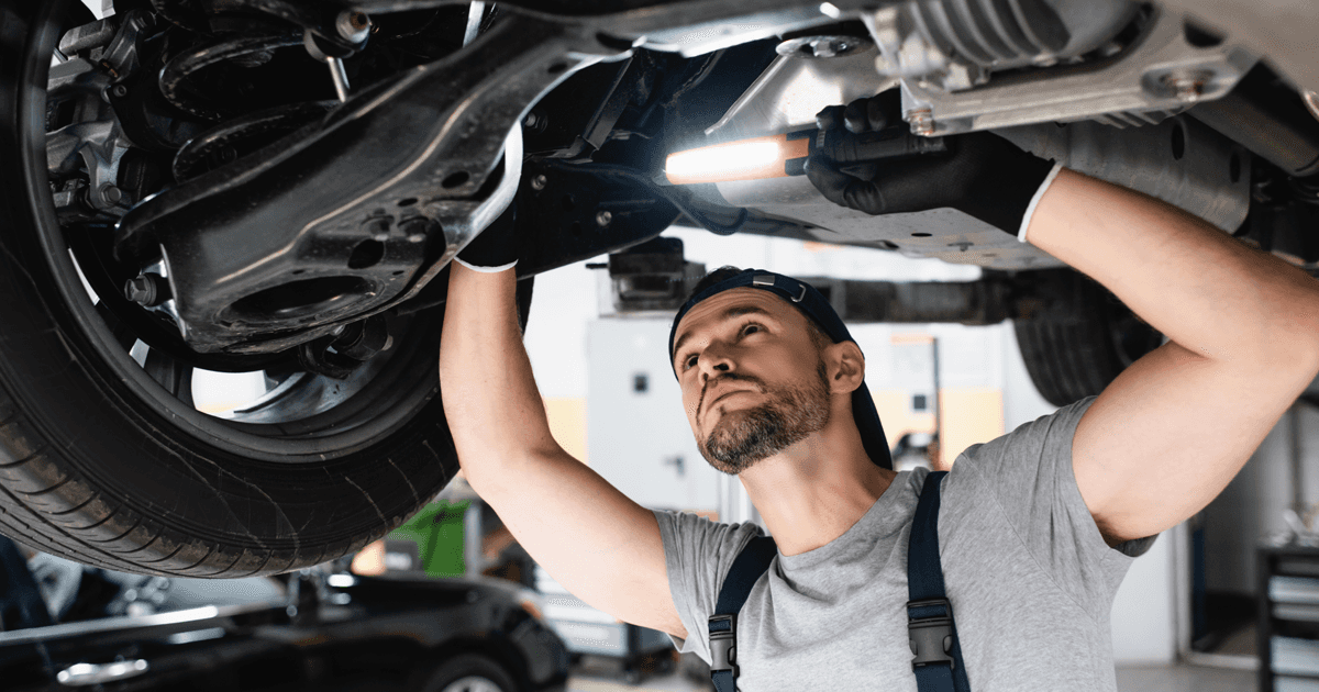 A service technician working under a vehicle in the service center.