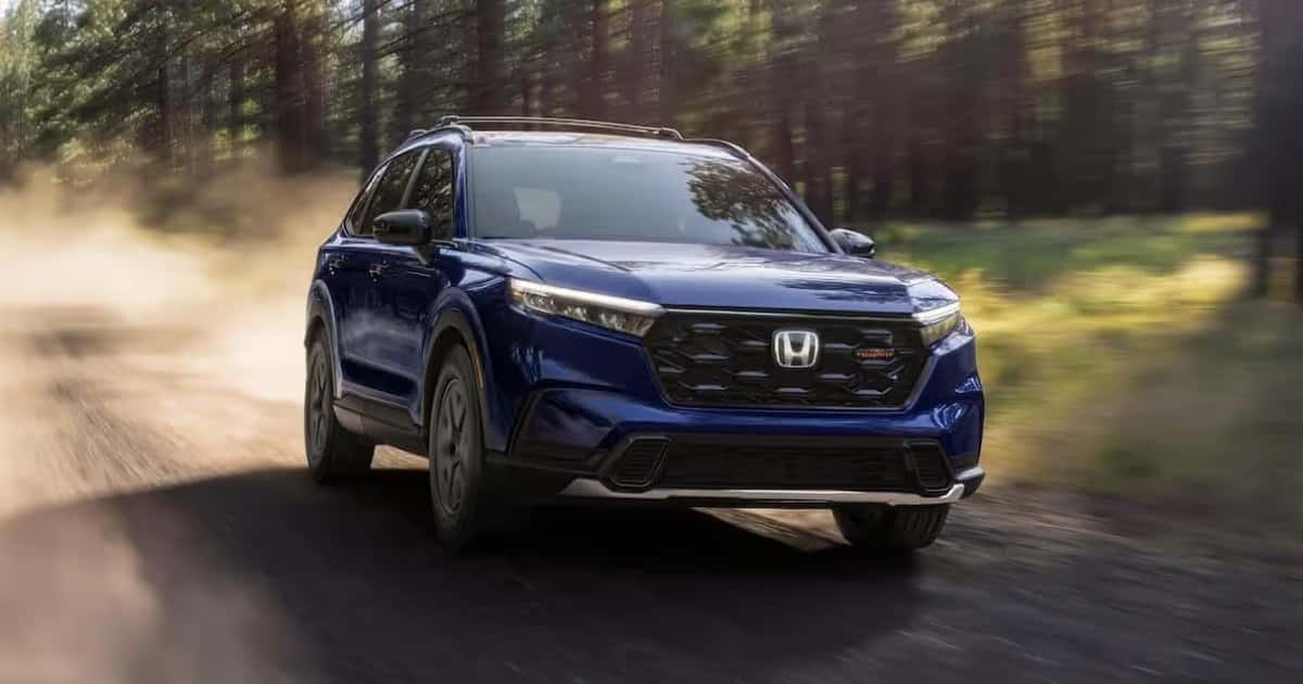 A Honda CR-V Hybrid in Canyon River Blue Metallic driving on a dirt road.