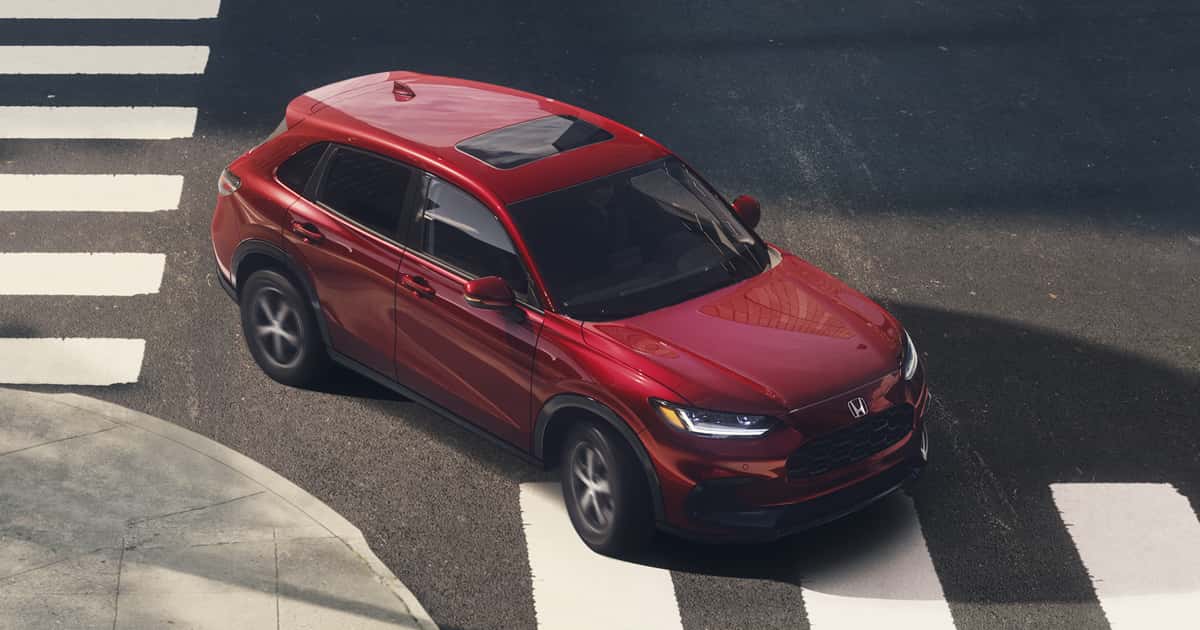 A red Honda HR-V turning the corner on a city street.