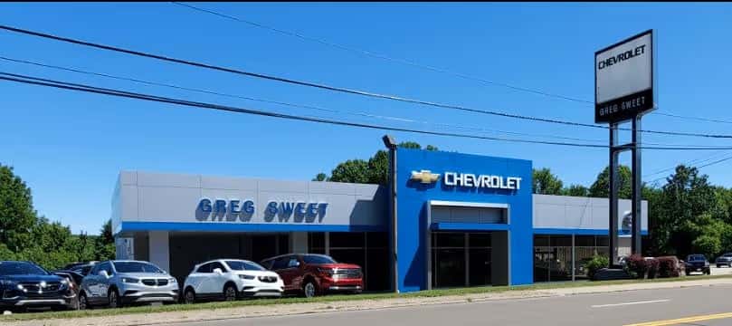 A family walking towards a Chevrolet vehicle in the driveway.