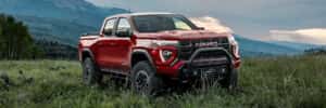 red gmc canyon parked in the grass