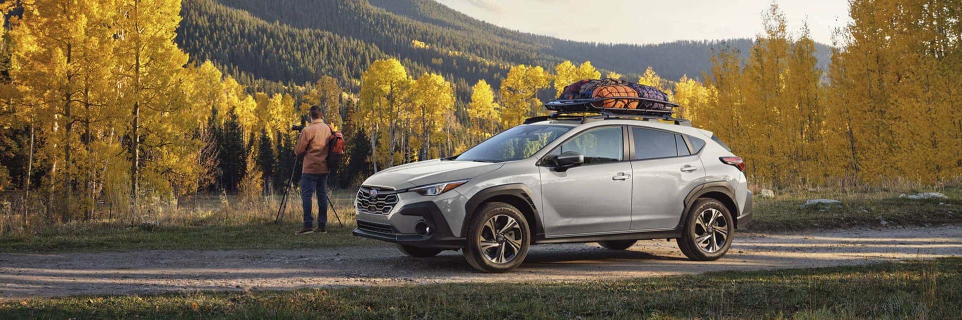 2026 subaru crosstrek parked in front of trees next to person