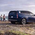 A blue Hyundai IONIQ 9 parked on a beach with a family approaching it