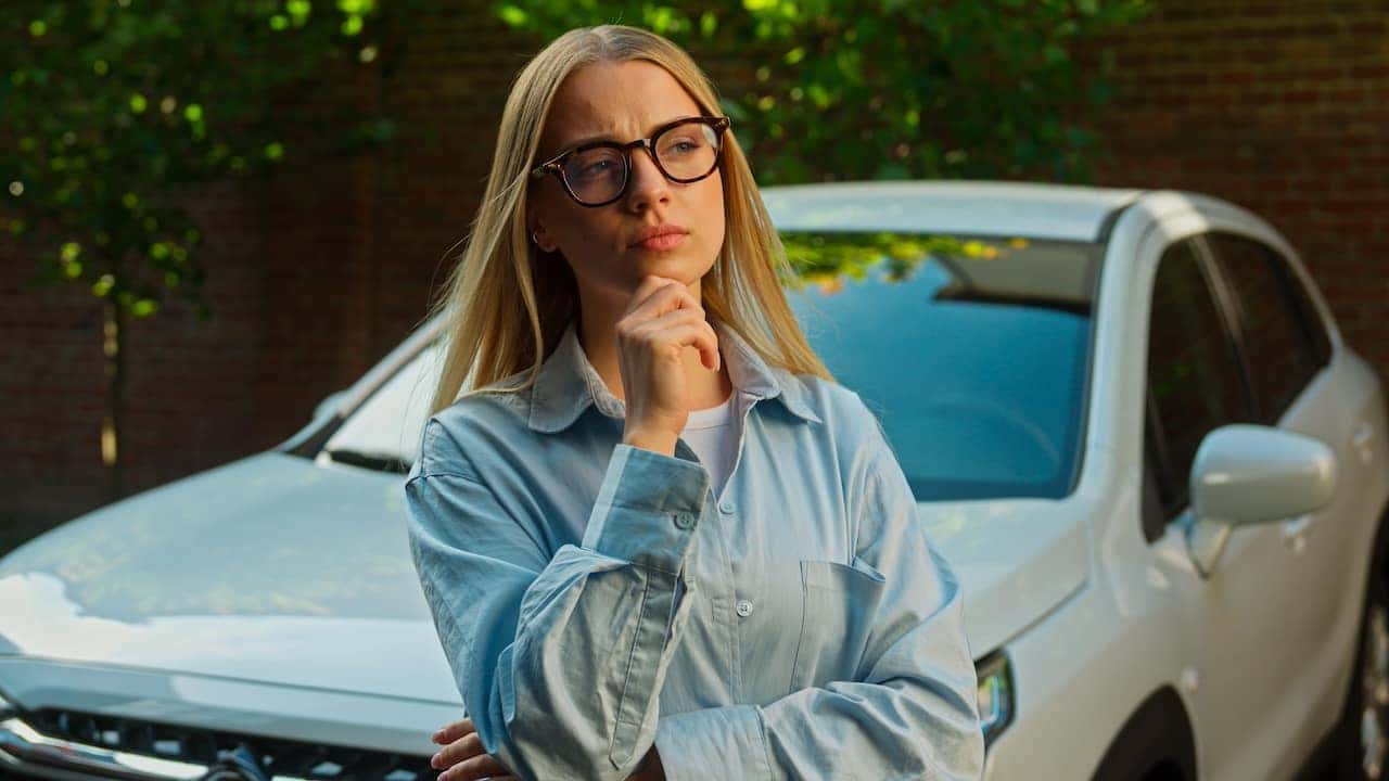 A person thinking in front of a car