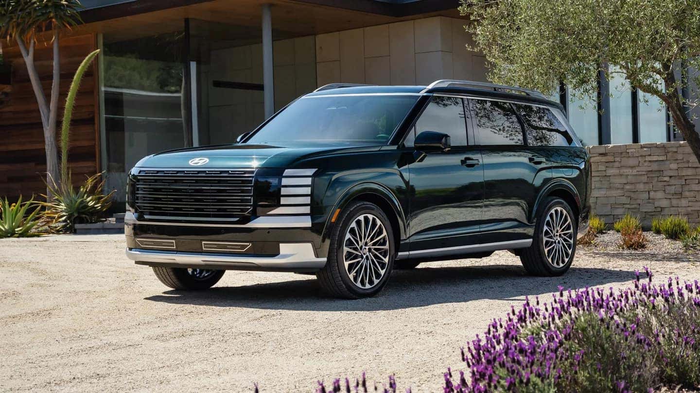 A teal Hyundai Palisade parked in front of a nice house