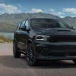 A black 2023 Dodge Durango driving in front of a hilly wilderness