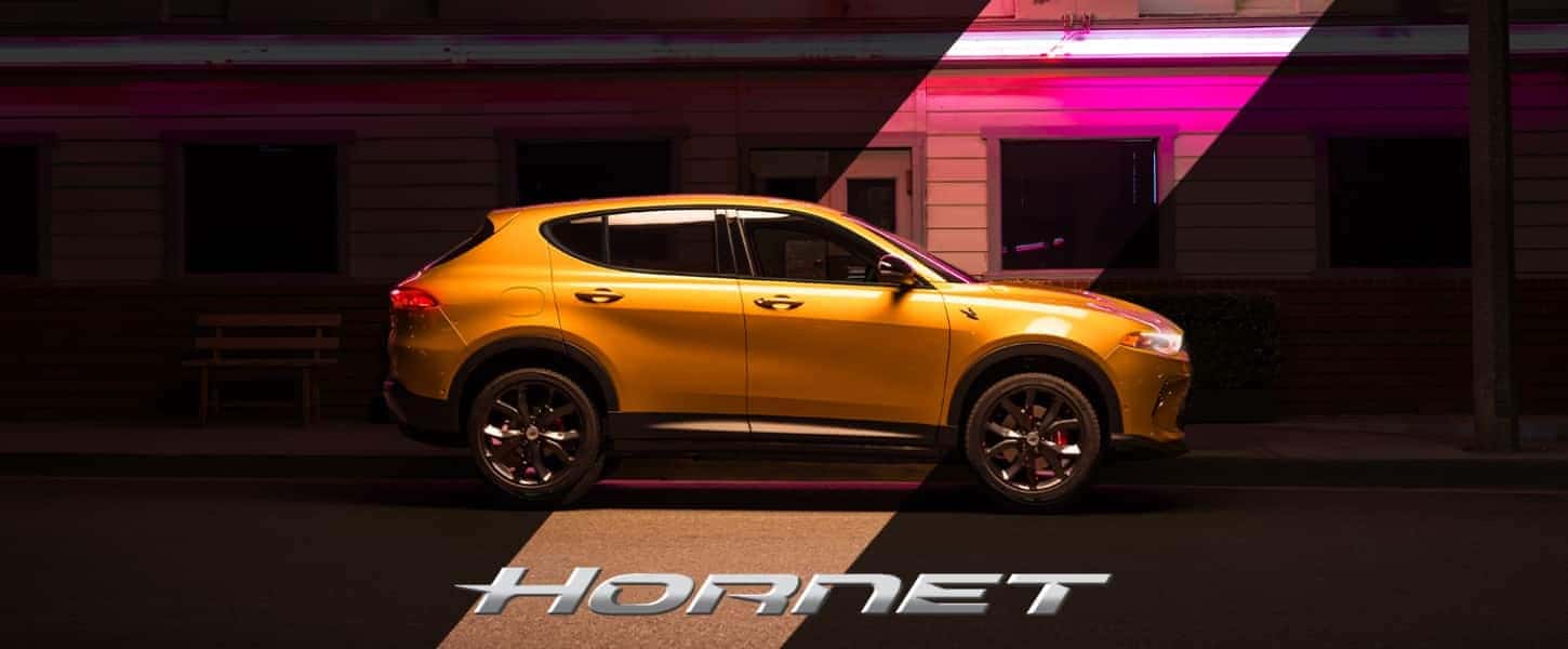 Yellow 2025 Dodge Hornet parked under neon lights with bold Hornet branding, creating a bold urban vibe.