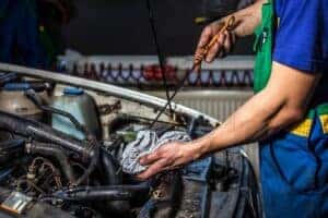 Oil change close-up under hood with mechanic.