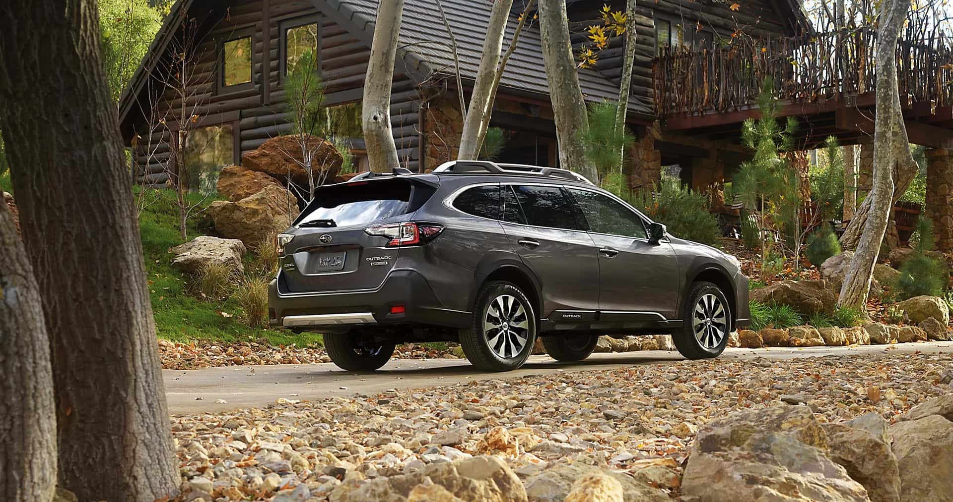 2025 Sbaru Outback parked in front of a cabin in the fall
