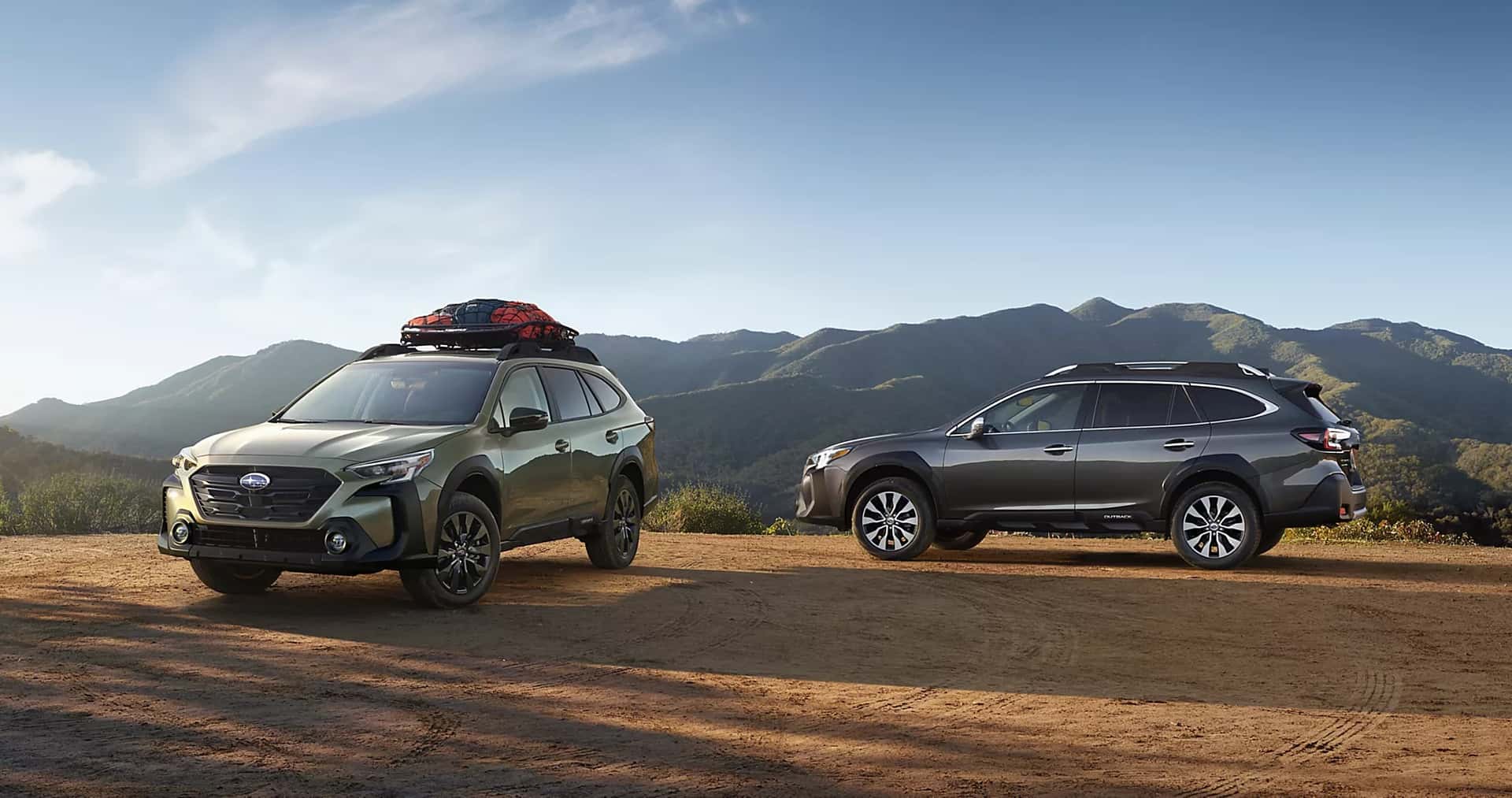 Three Subarus parked on a hill overlooking the mountains.