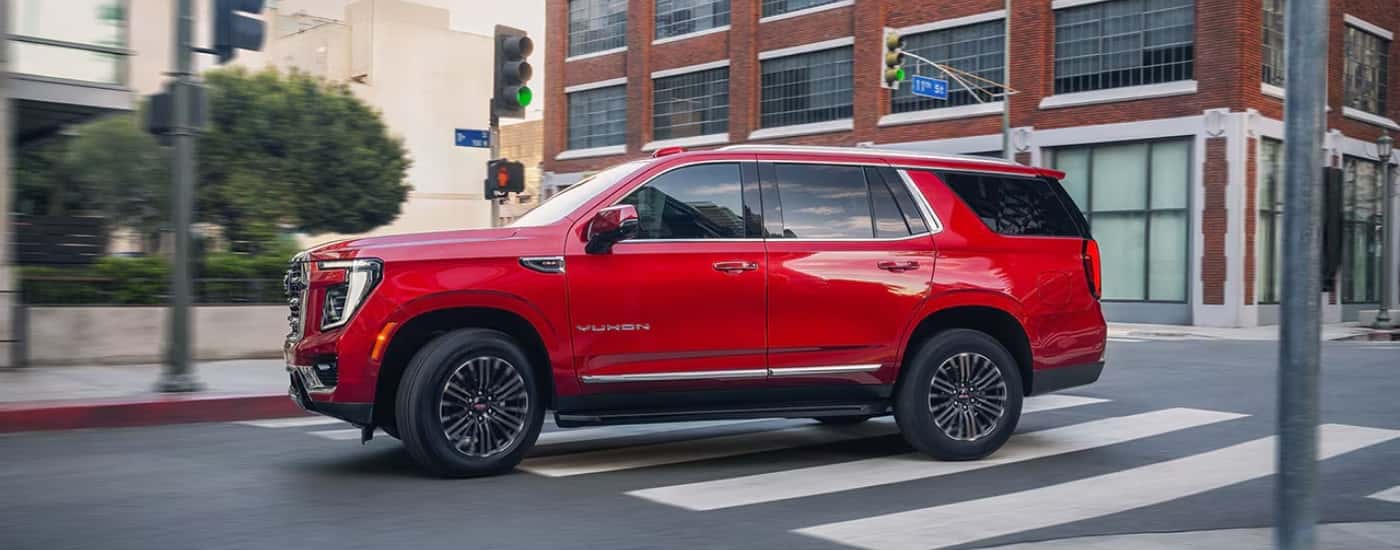 A red 2025 GMC Yukon driving on a city street.