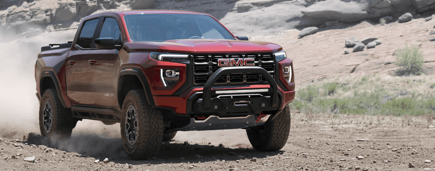 Red GMC Canyon driving down a trail
