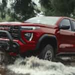 Red 2026 GMC Canyon AT4X driving through a river