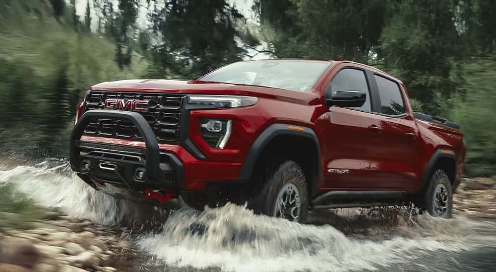 Red 2026 GMC Canyon AT4X driving through a river