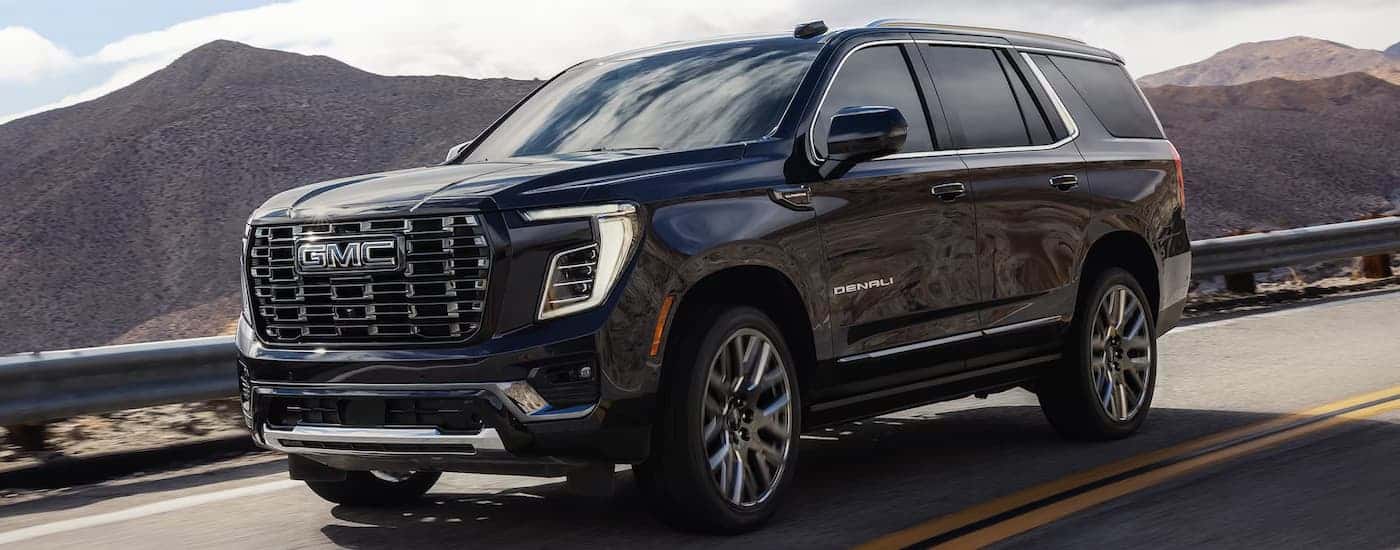 A black 2026 GMC Yukon XL Denali driving down a road
