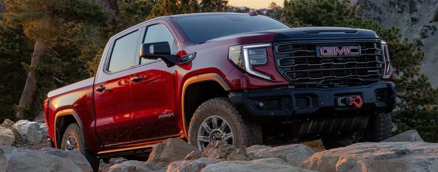 Red 2026 GMC Sierra 1500 AT4X driving over rocks.