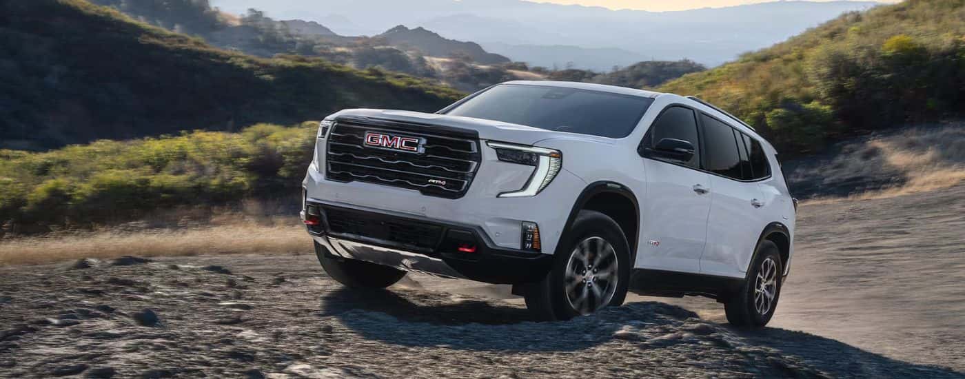 White 2026 GMC Acadia AT4 driving up rocks