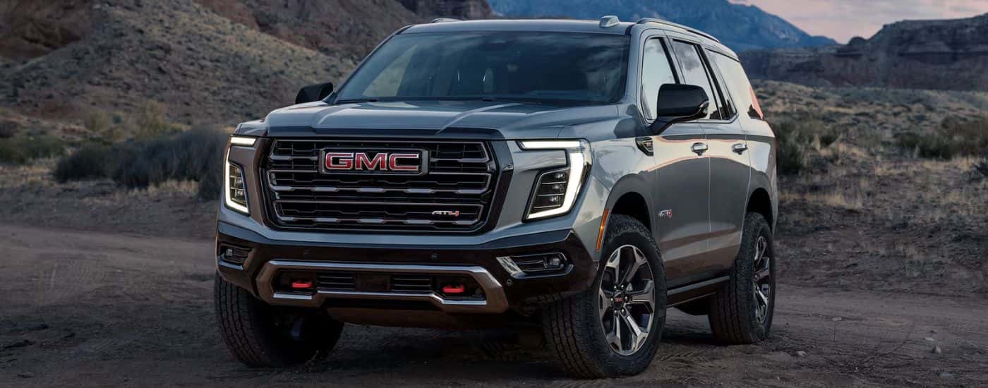 A gray 2026 GMC Yukon AT4 parked on a dirt mountain terrain.
