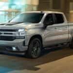 A silver 2023 Chevy Silverado 1500 RST Rally is driving to a used Chevy dealer.