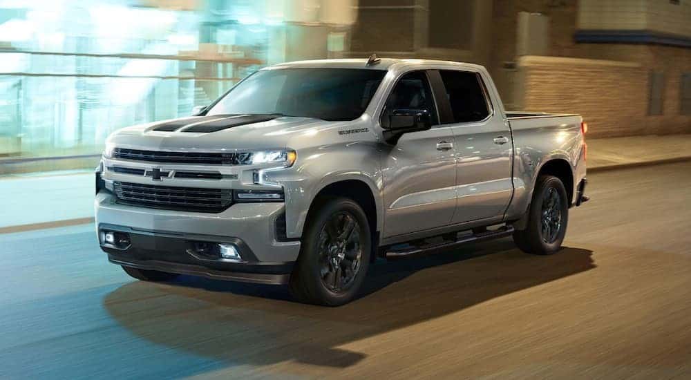 A silver 2023 Chevy Silverado 1500 RST Rally is driving to a used Chevy dealer.