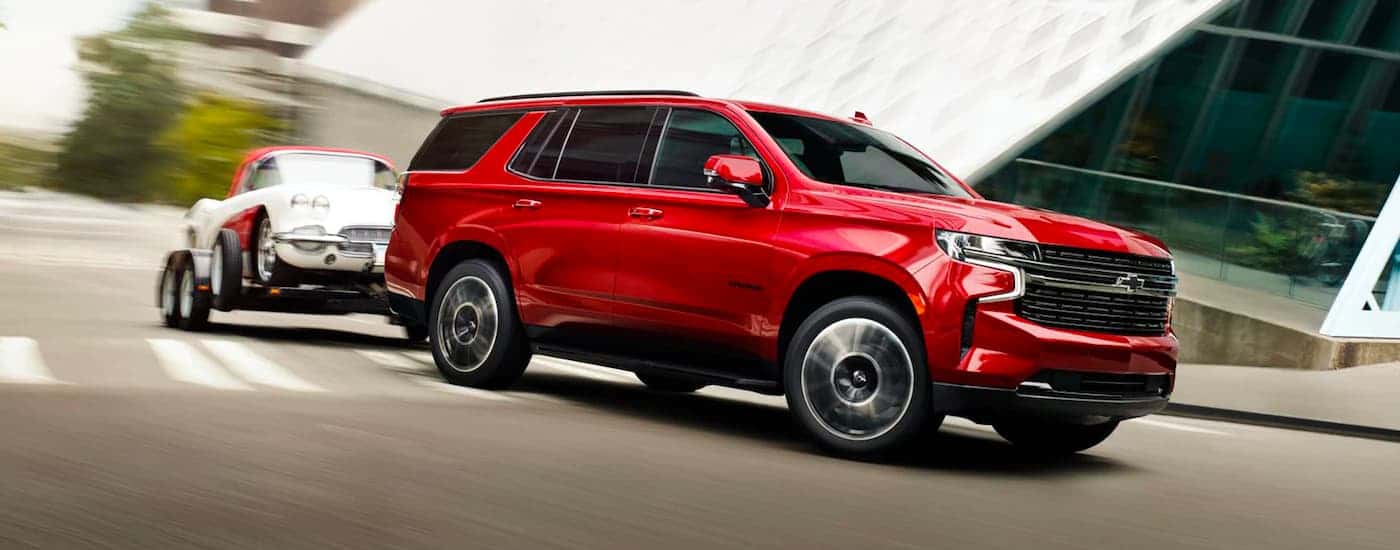 Red 2023 Chevy Tahoe towing a car from a Chevy dealer near West Columbia.