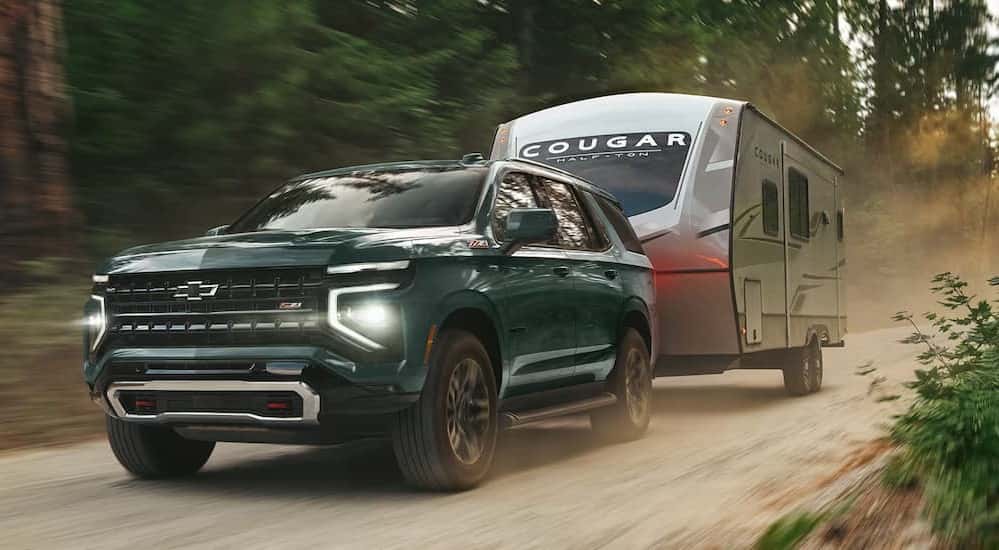 A green 2026 Chevy Tahoe Z71 towing a trailer.