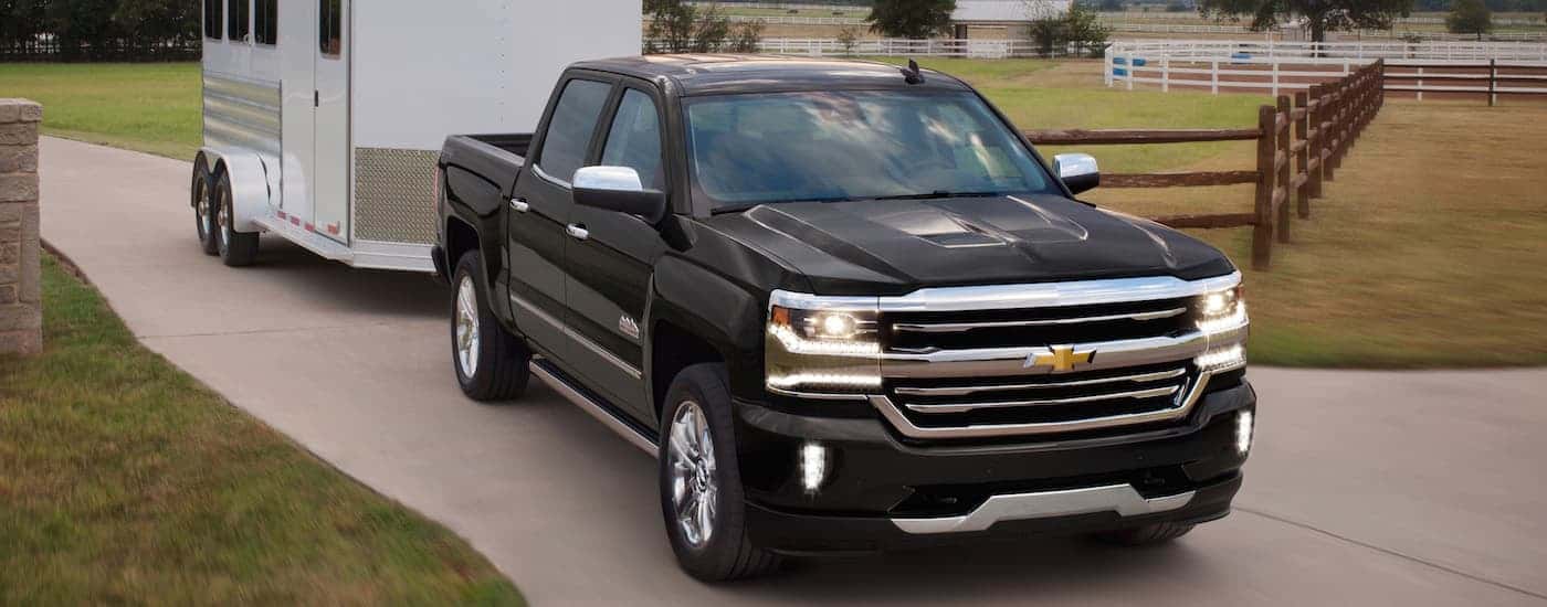 A black 2021 Chevy Silverado 2500 HD High Country towing a trailer.