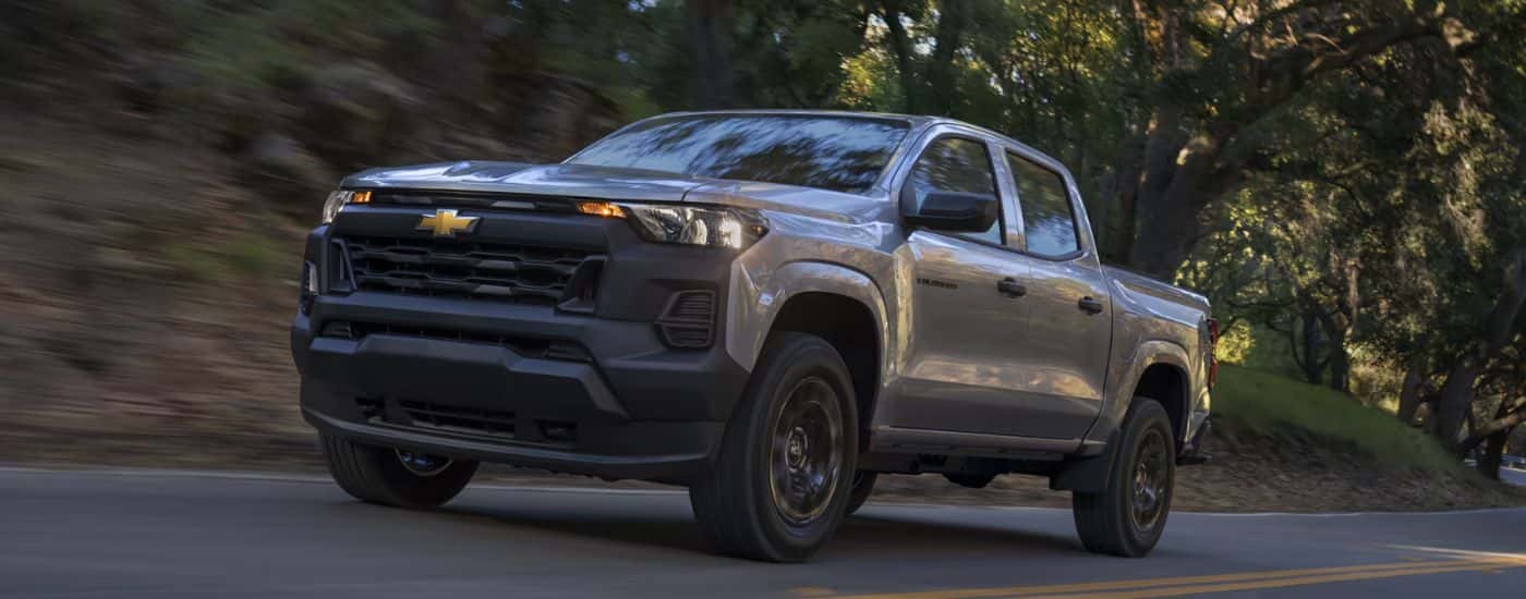 Grey 2026 Chevy Colorado driving down a road.